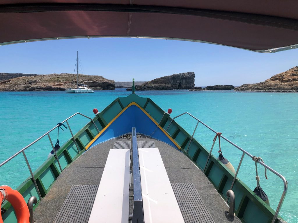 photo of luzzu with comino blue lagoon in background